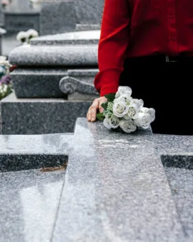 woman-in-red-blouse-putting-flowers-to-a-loved-one-in-the-cemetery-scaled-280x350